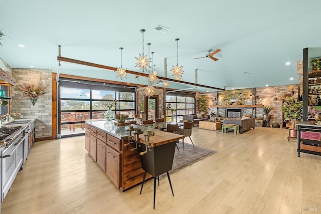 kitchen featuring visible vents, a center island, hanging light fixtures, light wood-style floors, and ceiling fan with notable chandelier