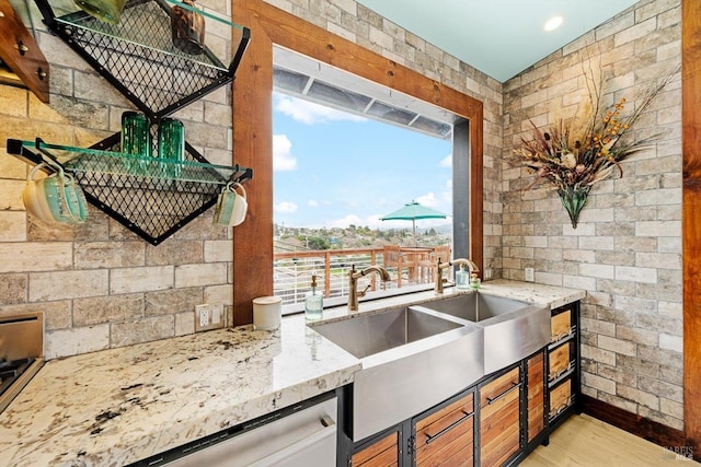 kitchen featuring light stone counters, light wood-type flooring, a sink, and stainless steel dishwasher