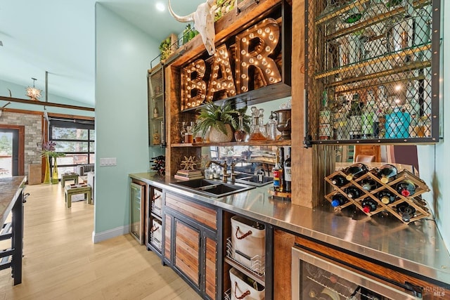 bar featuring light wood finished floors, beverage cooler, lofted ceiling, indoor wet bar, and a sink