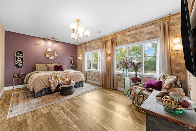 bedroom with an accent wall, multiple windows, wood finished floors, and rail lighting