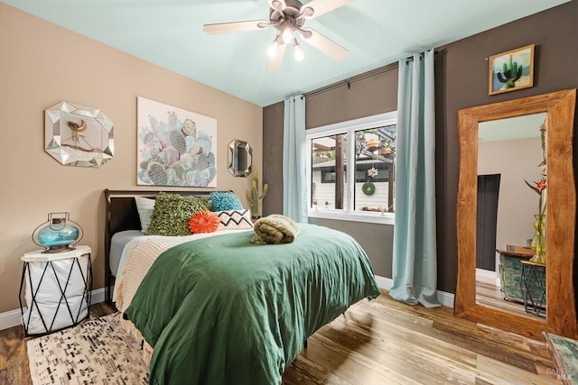 bedroom featuring ceiling fan, baseboards, and wood finished floors