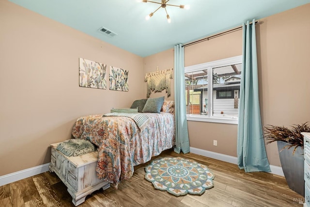 bedroom with wood finished floors, visible vents, and baseboards