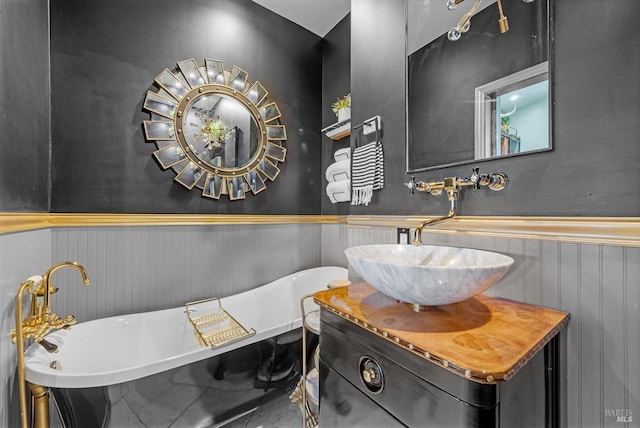 bathroom with a soaking tub, wainscoting, and vanity