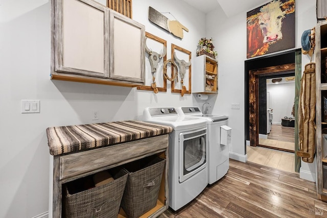 washroom with washer and dryer, cabinet space, baseboards, and wood finished floors