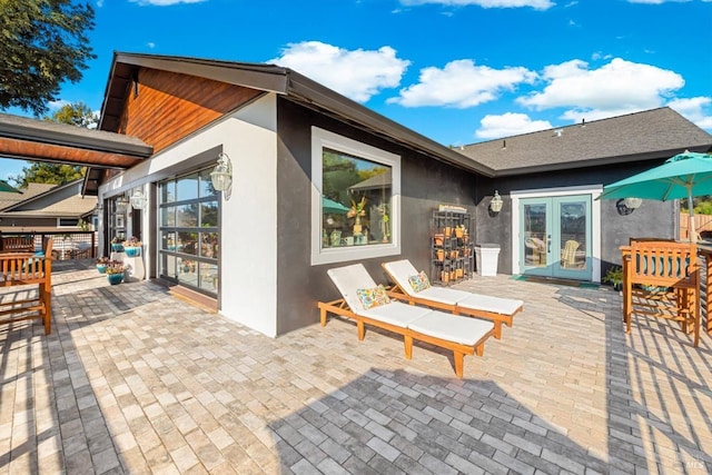 rear view of property with stucco siding, a patio area, and french doors