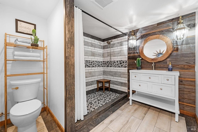 bathroom featuring visible vents, toilet, wood tiled floor, a tile shower, and vanity