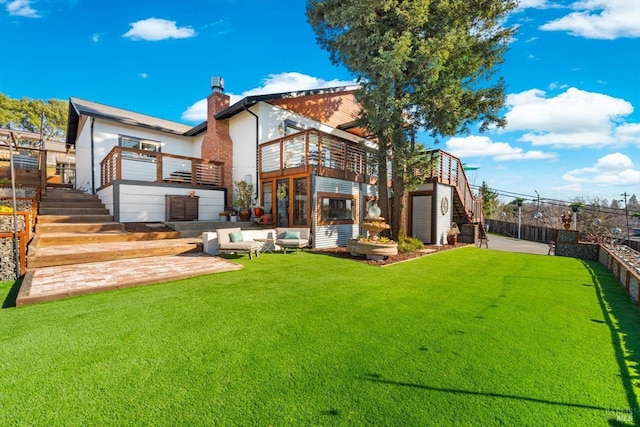 back of house with a yard, a chimney, a patio, stairway, and fence