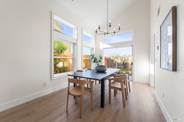 dining area with light wood finished floors, a wealth of natural light, and a notable chandelier