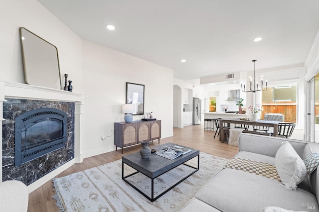 living area featuring visible vents, arched walkways, a high end fireplace, wood finished floors, and recessed lighting