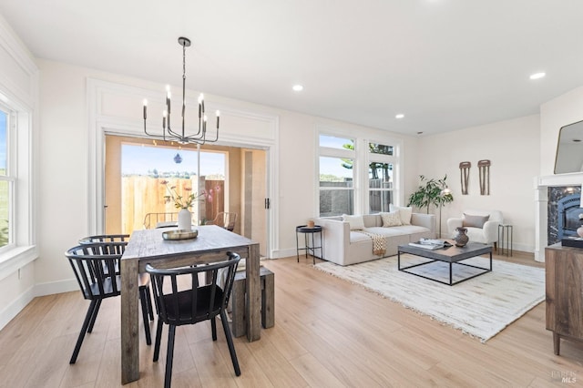 dining area with a glass covered fireplace, baseboards, light wood finished floors, and recessed lighting