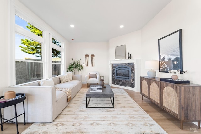 living area with recessed lighting, light wood finished floors, and a premium fireplace