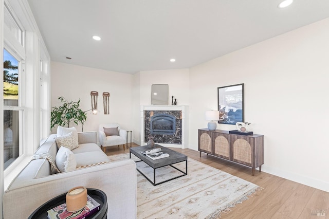 living room with recessed lighting, light wood-style flooring, baseboards, and a premium fireplace