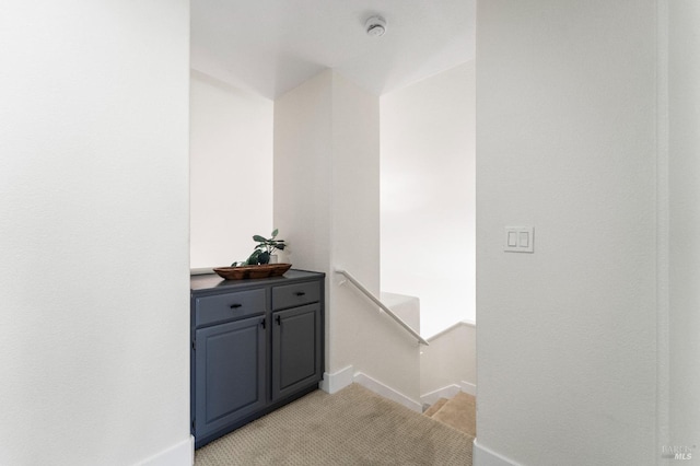 interior space featuring light carpet, an upstairs landing, and baseboards