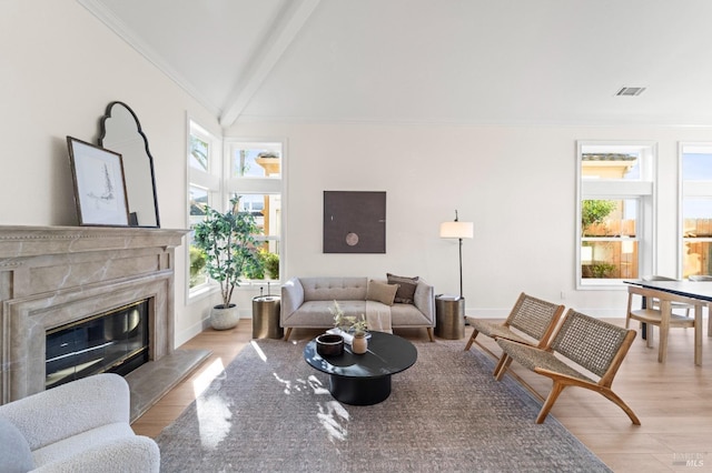 living area featuring visible vents, crown molding, light wood finished floors, and a premium fireplace