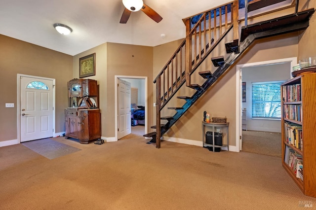 foyer entrance with ceiling fan and carpet flooring