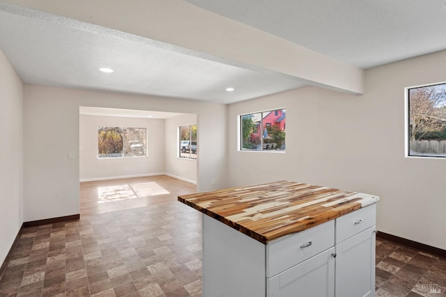 kitchen with white cabinetry, a center island, a textured ceiling, and butcher block countertops