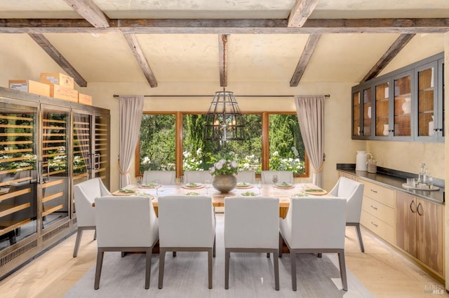 dining space with a chandelier, lofted ceiling with beams, and light hardwood / wood-style flooring