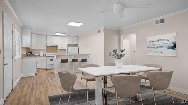 dining space with ceiling fan, crown molding, and light hardwood / wood-style flooring