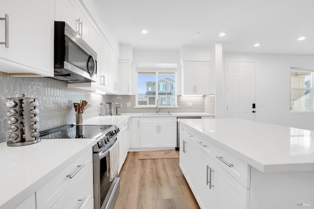 kitchen with white cabinetry, appliances with stainless steel finishes, decorative backsplash, light hardwood / wood-style flooring, and sink