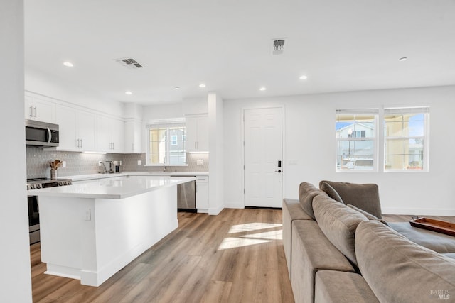 kitchen featuring white cabinets, appliances with stainless steel finishes, light hardwood / wood-style floors, and a kitchen island