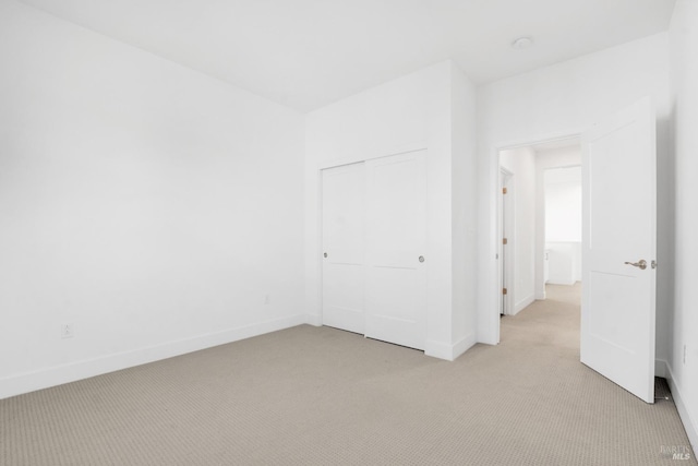 unfurnished bedroom with light carpet and a closet