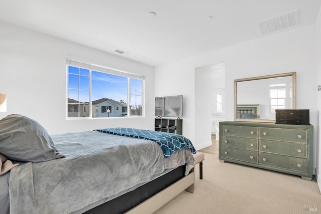 bedroom with multiple windows, light carpet, and ensuite bath