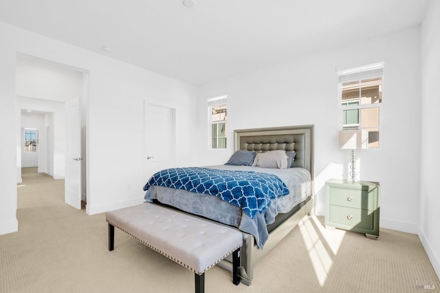 bedroom featuring light colored carpet and multiple windows