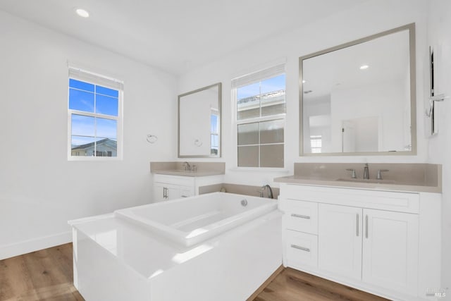 bathroom with wood-type flooring, a tub to relax in, and vanity