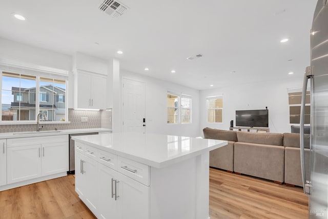 kitchen featuring white cabinetry, backsplash, a kitchen island, and sink