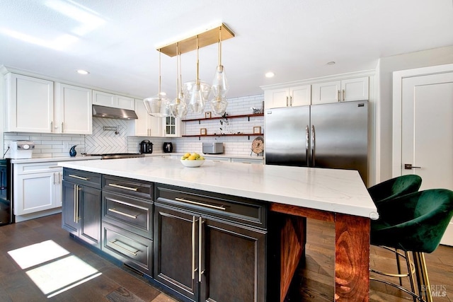 kitchen featuring a kitchen island, appliances with stainless steel finishes, white cabinetry, backsplash, and a kitchen bar