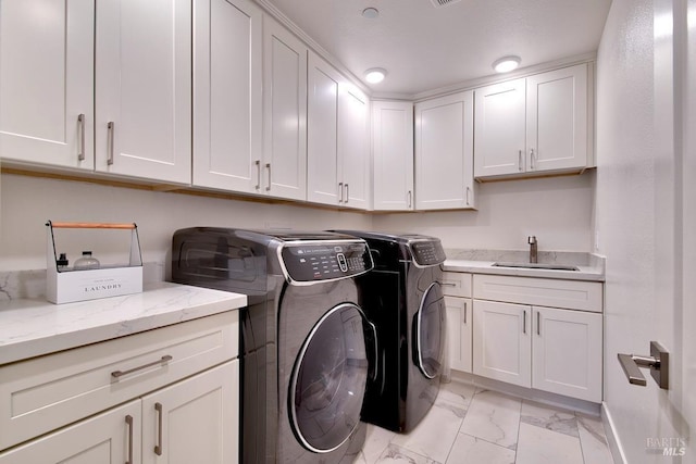 clothes washing area featuring sink, washer and clothes dryer, and cabinets