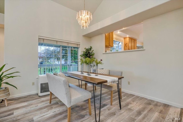 dining room featuring a chandelier, light hardwood / wood-style floors, and high vaulted ceiling