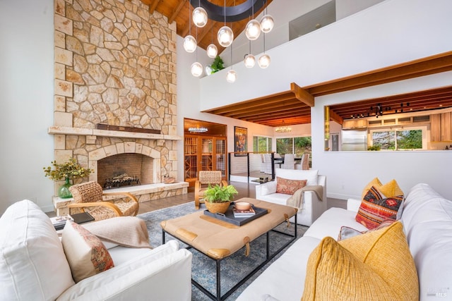 living room featuring a wealth of natural light, a stone fireplace, wood ceiling, and beam ceiling