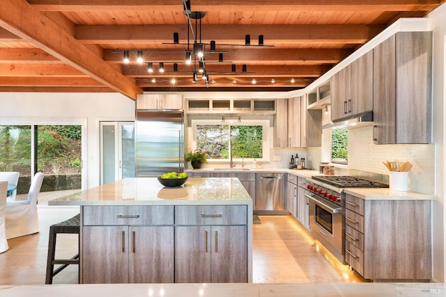 kitchen with high end appliances, a center island, hanging light fixtures, and tasteful backsplash