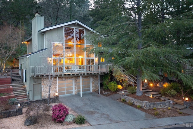 view of front of house with stairway, an attached garage, a chimney, and driveway