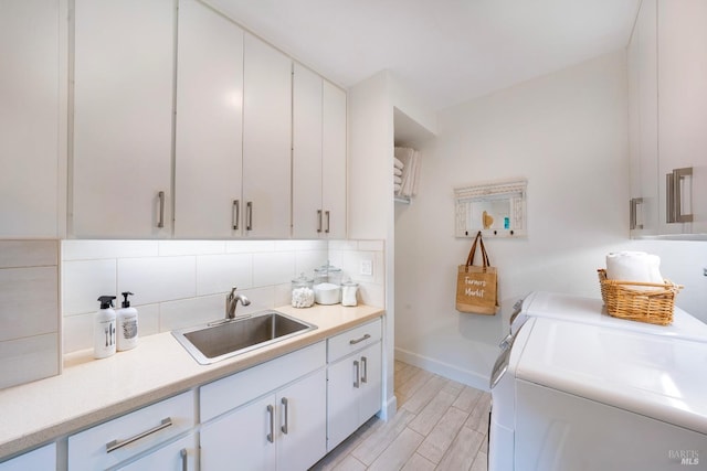 laundry room with cabinets, washer and clothes dryer, and sink