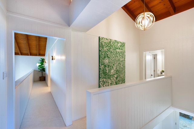 corridor featuring vaulted ceiling with beams, light carpet, and wooden ceiling