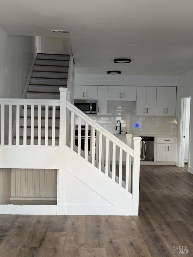 staircase featuring sink and hardwood / wood-style flooring