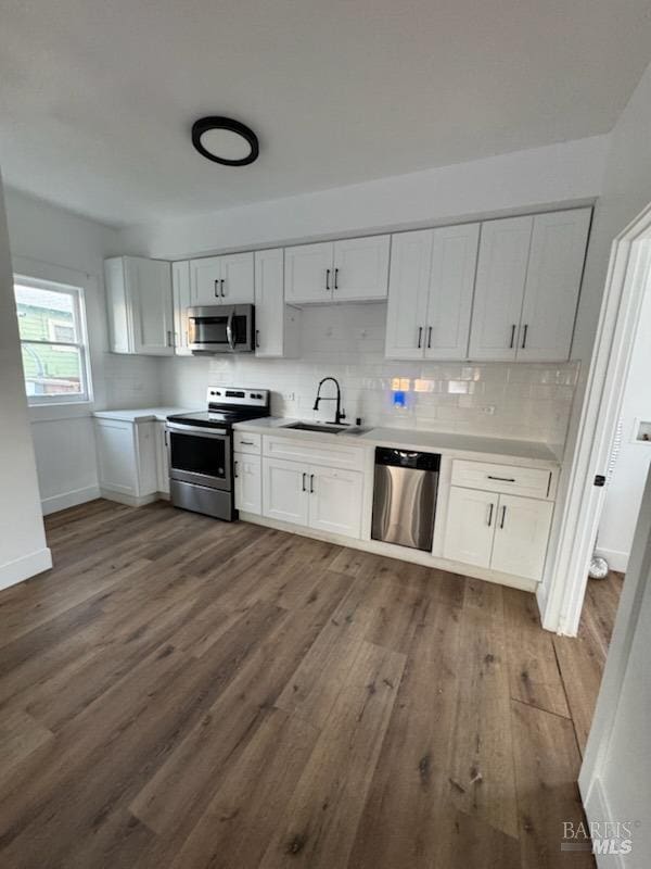 kitchen with dark wood-type flooring, stainless steel appliances, sink, and white cabinets