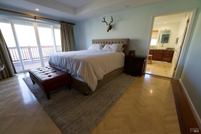 bedroom with light parquet flooring, connected bathroom, and access to exterior