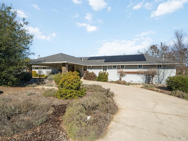 ranch-style house featuring driveway and solar panels