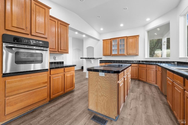 kitchen featuring a center island, oven, vaulted ceiling, light hardwood / wood-style flooring, and black electric cooktop