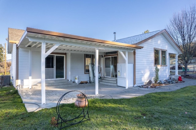 back of house with central AC unit and a yard