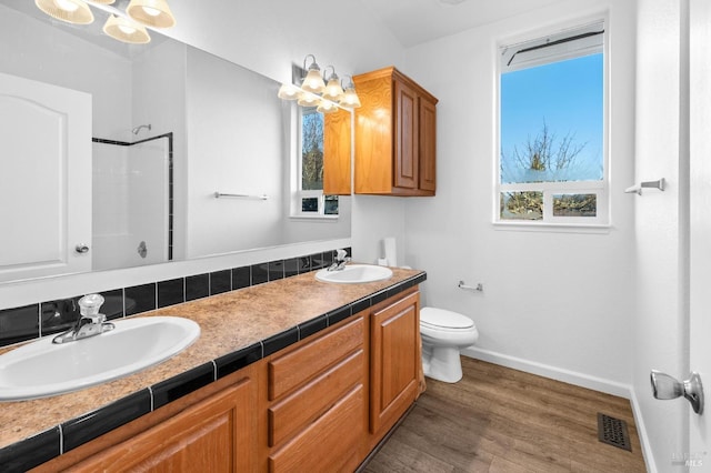 bathroom featuring toilet, a shower, a notable chandelier, wood-type flooring, and vanity