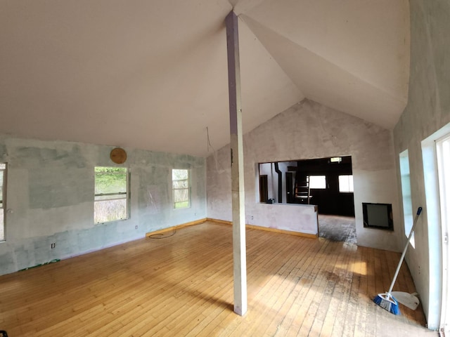 unfurnished living room with hardwood / wood-style flooring, a fireplace, and high vaulted ceiling