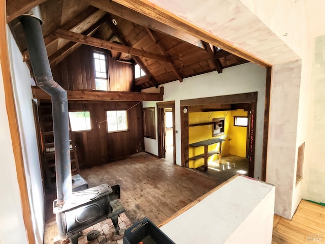 interior space featuring a wood stove, high vaulted ceiling, and beam ceiling