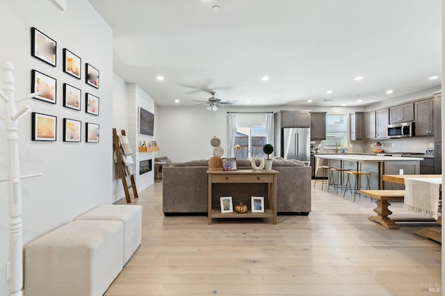 living room with ceiling fan and light hardwood / wood-style flooring