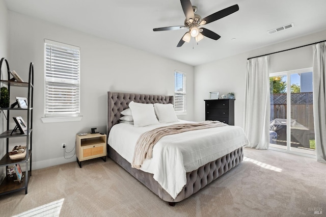 bedroom with ceiling fan, light colored carpet, multiple windows, and access to outside