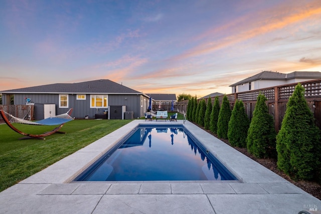 pool at dusk featuring a yard