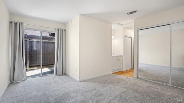 unfurnished bedroom with access to exterior, ensuite bath, a closet, and light carpet